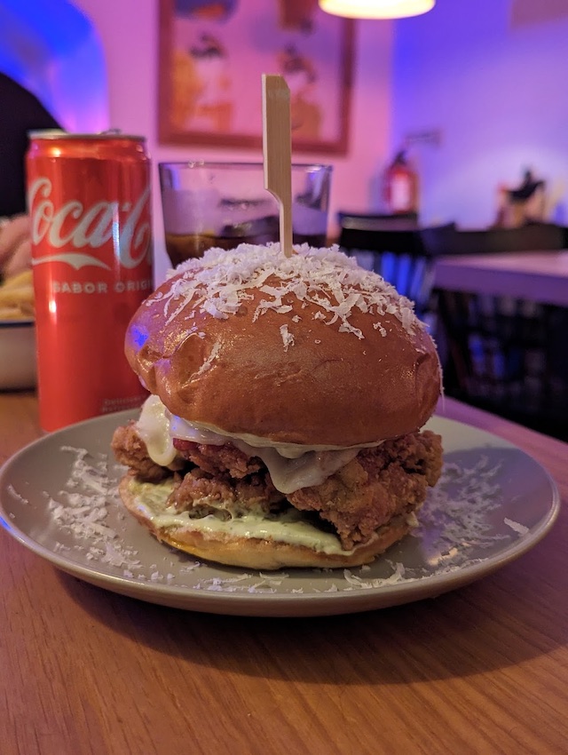 a chicken burger on a plate, covered in shredded cheese